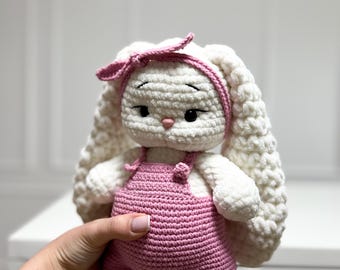 オーバーオールを着たかぎ針編みのウサギ。手作りのウサギのウサギ人形。赤ちゃんへのギフト。