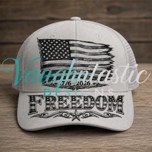 May include: A light gray trucker hat featuring a black and white graphic of a distressed American flag above the date 7/16/2026. The word FREEDOM is printed in large, bold, block lettering across the lower front panel with a star and scroll design.