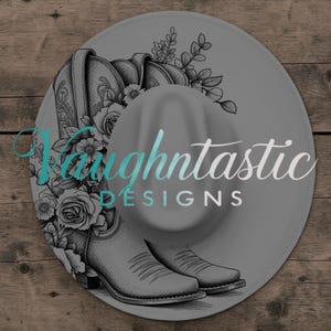 Könnte beinhalten: Ein grauer Cowboyhut mit floralem und Stiefel-Design. Der Hut zeigt eine detaillierte Illustration von Cowboy-Stiefeln und Rosen, mit dem Text "Faughtntastic DESIGNS" in einer Farbverlaufs-Schriftart. Das Design ist vor einem Holz Hintergrund.