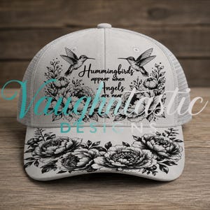 May include: A light gray trucker hat featuring a black ink-style illustration of two hummingbirds and floral arrangements. The text reads, Hummingbirds appear when Angels are near. The design is printed on the front panel and the curved brim.