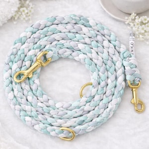 Könnte beinhalten: Geflochtene Hundeleine in Mint-, Weiß- und Grautönen mit goldfarbener Hardware. Die Leine ist auf einer weißen Oberfläche aufgerollt. Der Text "Mint Cloud" befindet sich oben im Bild.
