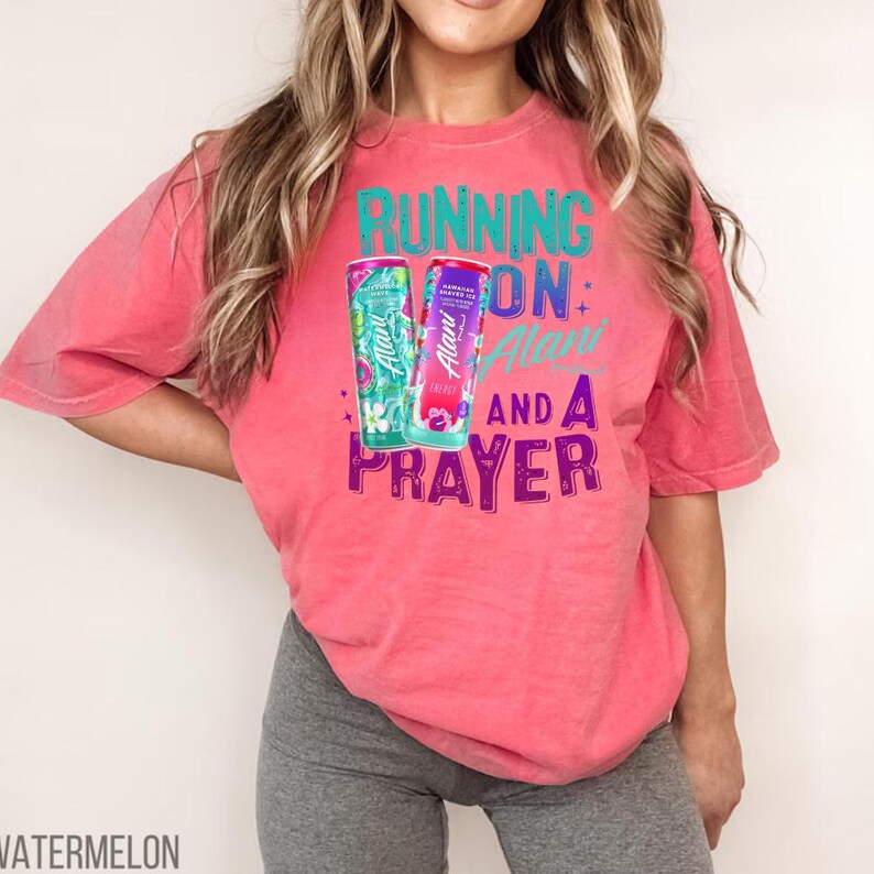 A woman wearing a pink t-shirt with a graphic design and text printed on it.