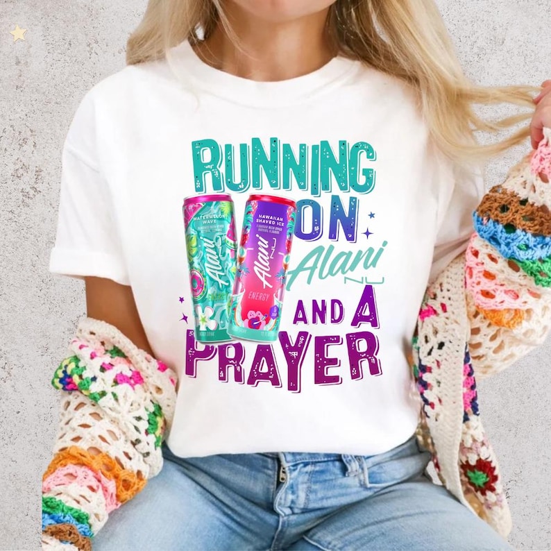 A person wearing a white t-shirt with a colorful graphic design featuring text and two cans of energy drinks.