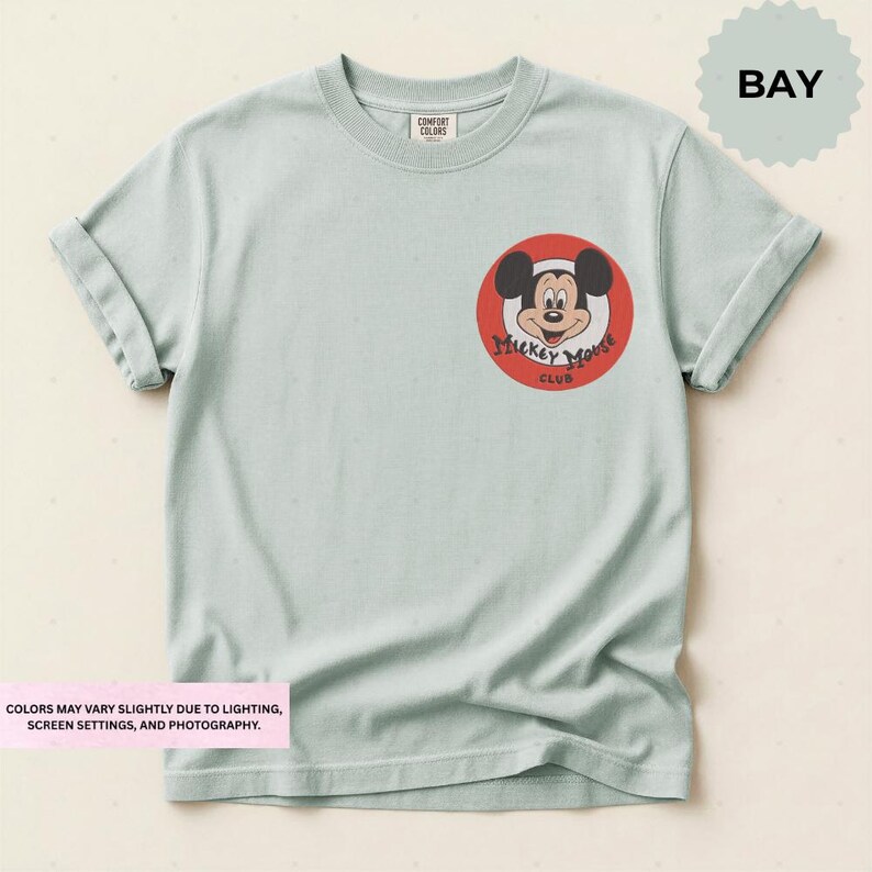 A light green t-shirt with a Mickey Mouse logo and text on the front.