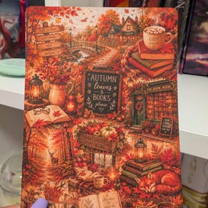 May include: A rectangular art print featuring a detailed autumn scene with orange and red foliage, a stone bridge, a cosy cottage, stacks of books, a sleeping fox, pumpkins, lanterns, and text including "Autumn leaves & books please" and "Cozy season".