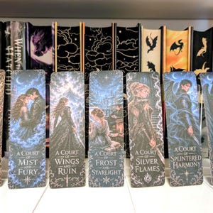May include: Seven rectangular bookmarks featuring fantasy illustrations and titles: A Court of Thorns and Roses, A Court of Mist and Fury, A Court of Wings and Ruin, A Court of Frost and Starlight, A Court of Silver Flames, A Court of Splintered Harmony, and A Court of Forgotten Melody.