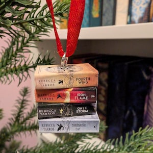 May include: A miniature stack of four book ornaments hanging from a red ribbon. The spines are labelled Fourth Wing, Iron Flame, Onyx Storm, and Threshing Day, all authored by Rebecca Yarros, featuring dragon graphics and distinct colour schemes.