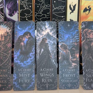 Può includere: Un set di cinque segnalibri rettangolari con illustrazioni fantasy e titoli della serie A Court of Thorns and Roses. Ogni segnalibro mostra personaggi e paesaggi unici in tonalità scure e suggestive con dettagli decorativi sui bordi.