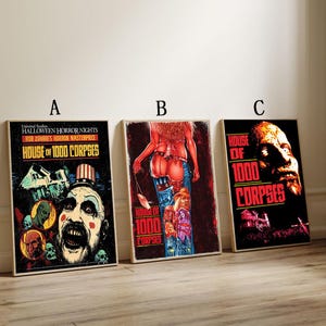 Op de afbeelding: Drie ingelijste horrorfilm posters. De posters tonen de tekst "HOUSE OF 1000 CORPSES" en diverse horror-thema illustraties. De posters zitten in houten frames en worden gepresenteerd tegen een neutrale achtergrond.