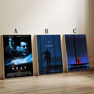 May include: Three framed movie posters for the film "Heat". The posters feature Al Pacino, Robert De Niro, and Val Kilmer. The posters have a blue and black color scheme with the word "HEAT" prominently displayed.