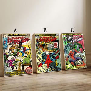 May include: Three framed vintage comic book covers featuring Spider-Man. The covers display colorful illustrations with text including "Amazing Spider-Man" and issue numbers. The comics are displayed on a light-colored surface.