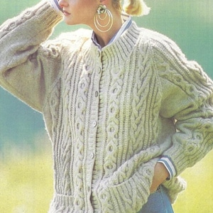 Può includere: Cardigan beige a maglia a trecce con chiusura a bottoni e colletto a coste. Il maglione presenta intricati motivi a treccia e un design strutturato. Le maniche hanno polsini a coste. Il cardigan è di colore neutro.