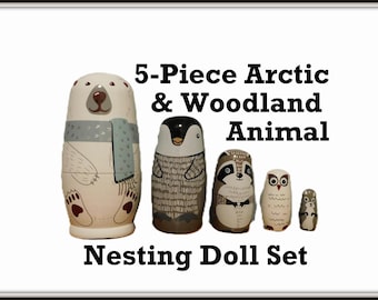 May include: A 5-piece nesting doll set featuring arctic and woodland animals. The set includes a polar bear, penguin, raccoon, owl, and a small squirrel. The dolls are painted in neutral tones with detailed animal features. The text on the image reads "5-Piece Arctic & Woodland Animal Nesting Doll Set."