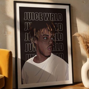 May include: A framed art print featuring a portrait of Juice WRLD. The artwork has a black background with the words "JUICE WRLD" in white. The portrait depicts a man with brown skin, wearing a white shirt, and looking to the side.