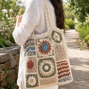 Può includere: Una borsa tote all'uncinetto color crema con un design patchwork. La borsa presenta vari motivi quadrati nei toni del beige, marrone, blu e verde, inclusi motivi floreali e geometrici. Ha un bordo smerlato e spallacci color crema.