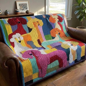Op de afbeelding: Een kleurrijke quilt met meerdere poedelhondontwerpen in verschillende kleuren, waaronder rood, geel, wit en roze. De quilt is gedrapeerd over een bruine leren bank, met een regenboog gestreepte rand. De kamer heeft een houten tafel en een grote plant in een pot.