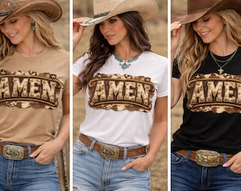 May include: Three women wearing t-shirts with the word "AMEN" in a western-style design. The shirts are tan, white, and black. Each woman wears a cowboy hat, blue jeans, and a brown belt with a decorative buckle.