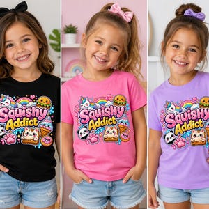 Può includere: Tre ragazze indossano magliette con la scritta "Squishy Addict" e grafiche colorate. Le magliette sono nere, rosa e viola. La grafica include un arcobaleno, un unicorno, un panda e vari alimenti.
