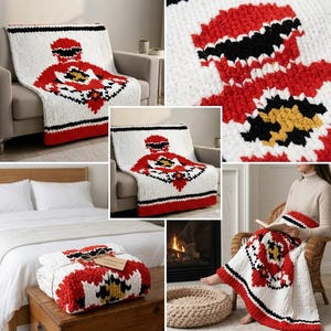 Può includere: Una coperta in maglia grossa con base bianca e un grande motivo grafico centrale in rosso, nero e giallo. La coperta presenta un bordo rosso spesso sul fondo e un aspetto morbido e testurizzato, mostrata drappeggiata su mobili e piegata.