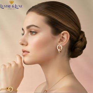 Könnte beinhalten: Eine Frau trägt goldfarbenen Schmuck, darunter Ohrringe, ein Armband und eine Halskette. Die Ohrringe haben ein Doppelreifen-Design mit römischen Ziffern. Armband und Halskette haben ebenfalls ein ähnliches kreisförmiges Design. Der Schmuck ist vor einem weichen, neutralen Hintergrund.