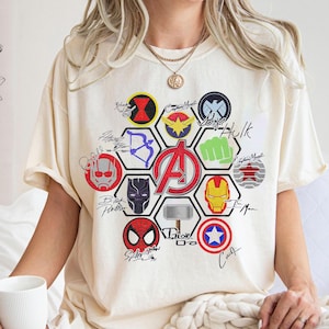 Pu&ograve; includere: T-shirt color crema con grafica del logo degli Avengers e simboli dei personaggi. Il design include Iron Man, Capitan America, Spider-Man e Thor. La maglietta ha maniche corte e una vestibilit&agrave; ampia.