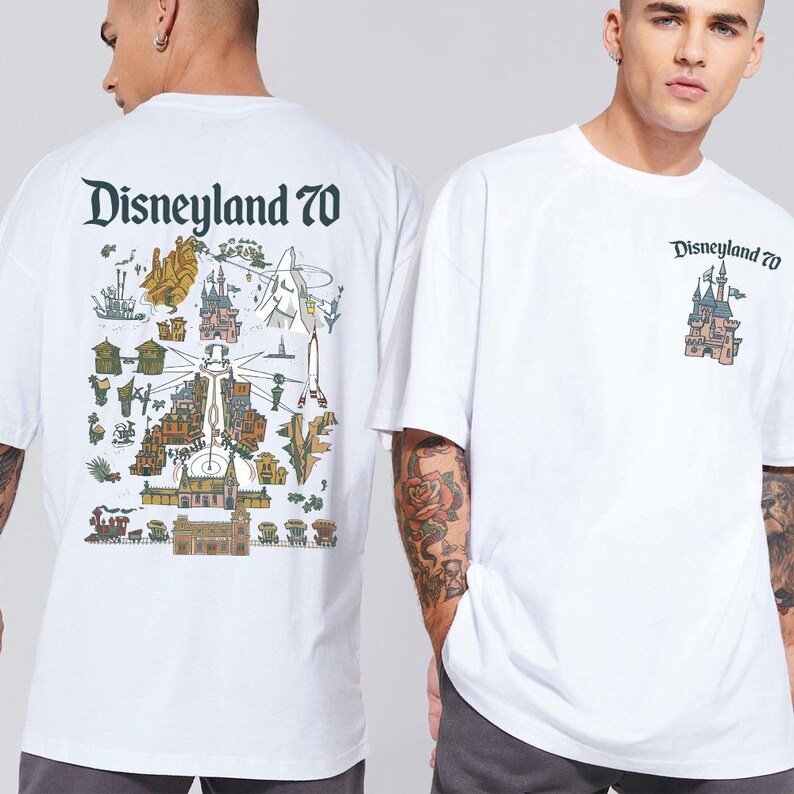Puede incluir: Una camiseta blanca de manga corta con el texto Disneyland 70. La parte delantera muestra un peque&ntilde;o gr&aacute;fico de un castillo. La parte trasera presenta una ilustraci&oacute;n grande y detallada de estilo mapa de atracciones de Disneyland.