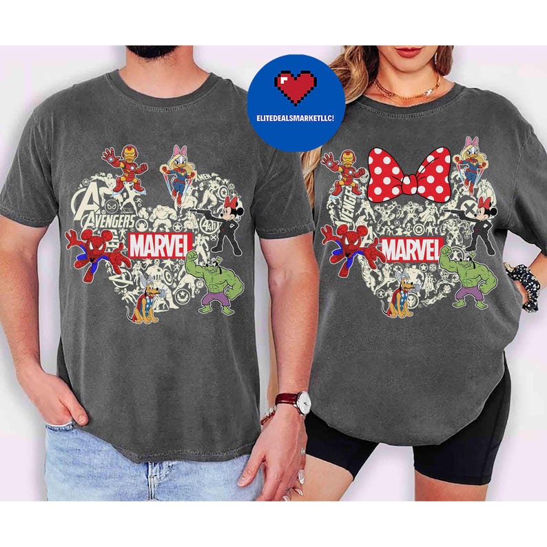 May include: Two charcoal gray t-shirts featuring a heart-shaped design with Marvel characters. The design includes Spider-Man, Hulk, Iron Man, and Mickey and Minnie Mouse. The word "MARVEL" is printed in white.