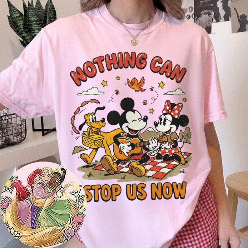 May include: A light pink t-shirt featuring a graphic print of Mickey Mouse playing a guitar, Minnie Mouse, and Pluto on a picnic blanket. The text "NOTHING CAN STOP US NOW" is printed in orange. A circular inset shows an illustration of three princesses.