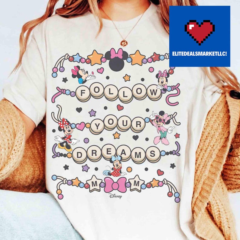 May include: Cream-colored t-shirt featuring the phrase "FOLLOW YOUR DREAMS" in a playful, circular design. Minnie Mouse characters and stars decorate the shirt. The Disney logo is at the bottom.