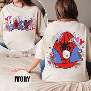 Puede incluir: Camiseta de color marfil con el nombre "JASON" en una fuente colorida de estilo c&oacute;mic, telara&ntilde;as y gr&aacute;ficos de personajes. La parte posterior muestra un gran emblema de ara&ntilde;a con ilustraciones de personajes y acentos de estrellas.