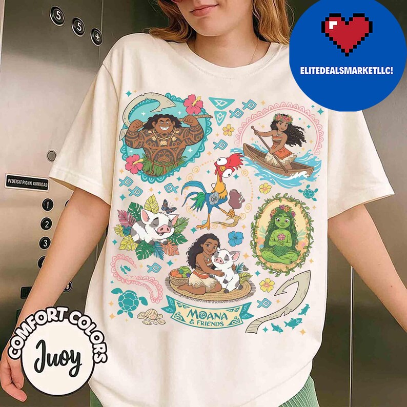 May include: Cream-colored t-shirt featuring colorful illustrations of characters from the animated film "Moana." The design includes images of Maui, Moana, Hei Hei, Pua, and other elements. The text "Moana & Friends" is also visible.