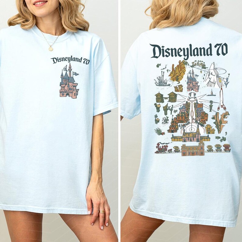 Puede incluir: Una camiseta azul claro con un peque&ntilde;o logotipo de Disneyland 70 y un gr&aacute;fico de castillo en el pecho izquierdo. La parte posterior muestra una ilustraci&oacute;n grande y detallada de un mapa de atracciones de Disneyland con el texto Disneyland 70.