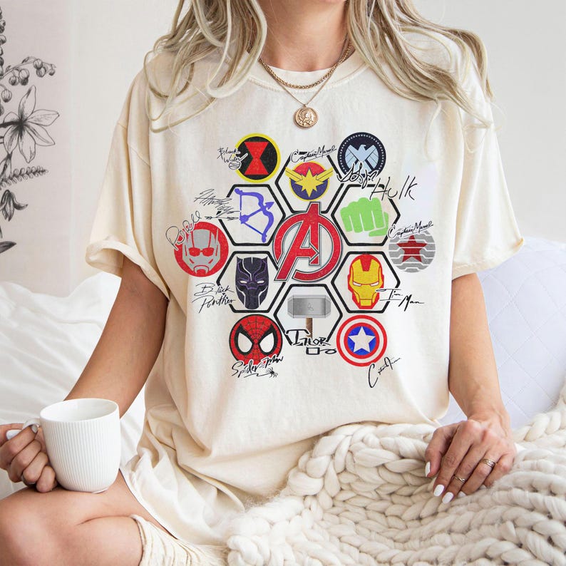 Pu&ograve; includere: T-shirt color crema con grafica del logo degli Avengers e simboli dei personaggi. Il design include Iron Man, Capitan America, Spider-Man e Thor. La maglietta ha maniche corte e una vestibilit&agrave; ampia.