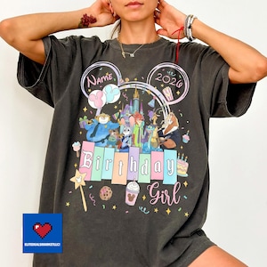 May include: Dark gray t-shirt with a colorful Disney-themed birthday design. The design includes the text "Name" and "2020" in Mickey Mouse ears, along with various Disney characters and the words "Birthday Girl".