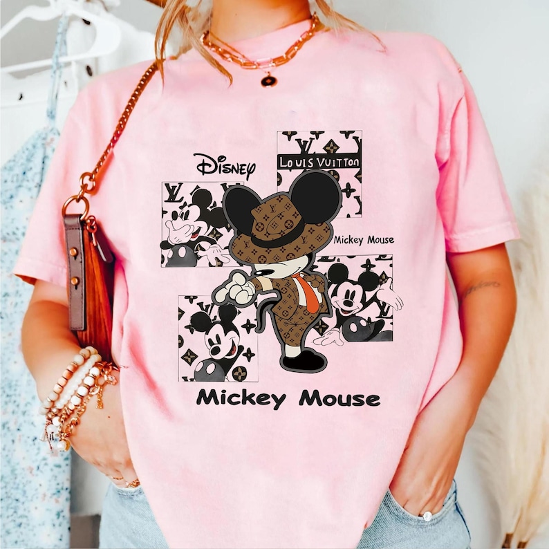 May include: Pink t-shirt featuring a Mickey Mouse graphic in a brown suit and hat, with the Disney and Louis Vuitton logos. The words "Mickey Mouse" are printed below the graphic.