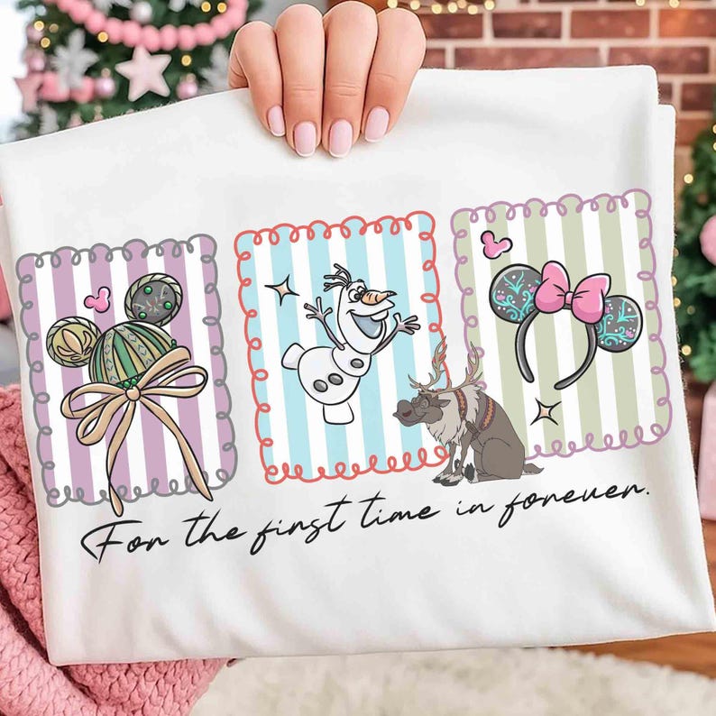 May include: White t-shirt featuring three framed illustrations. The illustrations include a Mickey Mouse-themed design with a bow, Olaf the snowman, and a pair of Minnie Mouse ears with a pink bow. The text "For the first time in forever" is printed at the bottom.