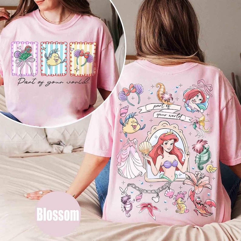 May include: Pink t-shirt featuring a front graphic with three framed images and the text "Part of your world." The back graphic showcases Ariel and other characters from The Little Mermaid. The shirt is a light pink color.