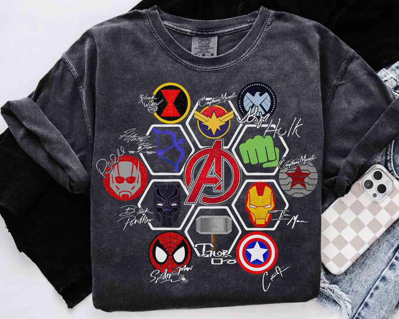 Pu&ograve; includere: T-shirt grigio scuro con loghi e firme di supereroi colorati. Il design include il logo degli Avengers al centro, circondato da emblemi di personaggi e firme. La maglietta &egrave; realizzata in un materiale morbido e confortevole.