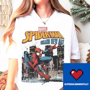 May include: White t-shirt with a Marvel Spider-Man graphic. The design features the words "Spider-Man Brand New Day" in yellow and the superhero in action against a city skyline. The shirt has a crew neck.