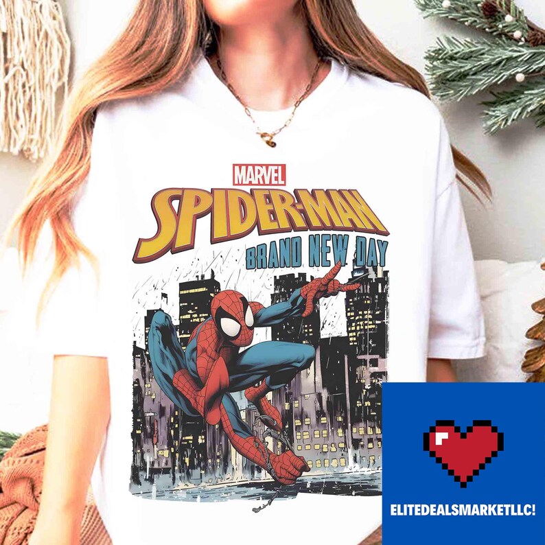 May include: White t-shirt with a Marvel Spider-Man graphic. The design features the words "Spider-Man Brand New Day" in yellow and the superhero in action against a city skyline. The shirt has a crew neck.