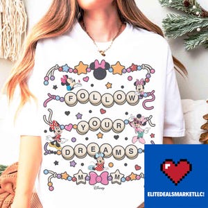 May include: White t-shirt featuring the text "FOLLOW YOUR DREAMS" with Minnie Mouse characters and decorative elements. The design includes stars, hearts, and bows. The Disney logo is at the bottom.