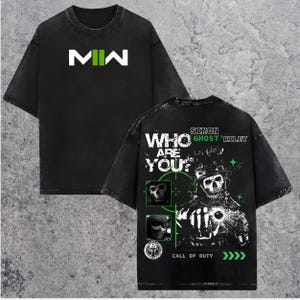 May include: Black graphic tee featuring the text "MW" in white and green on the front. The back of the shirt displays a skull graphic with the text "WHO ARE YOU?" and "SIMON GHOST RILEY" with the words "CALL OF DUTY".