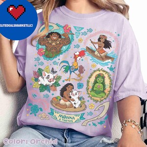May include: Orchid-colored t-shirt featuring a colorful graphic of characters from the animated film Moana. The design includes illustrations of Maui, Moana, Pua, Hei Hei, and other elements from the movie. The text "Moana & Friends" is also visible.