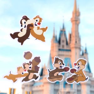 May include: Set of stickers featuring Chip and Dale cartoon characters. The stickers depict the chipmunks in various poses, including hugging, playing with acorns, and holding peanuts. The background shows a blurred image of a castle.