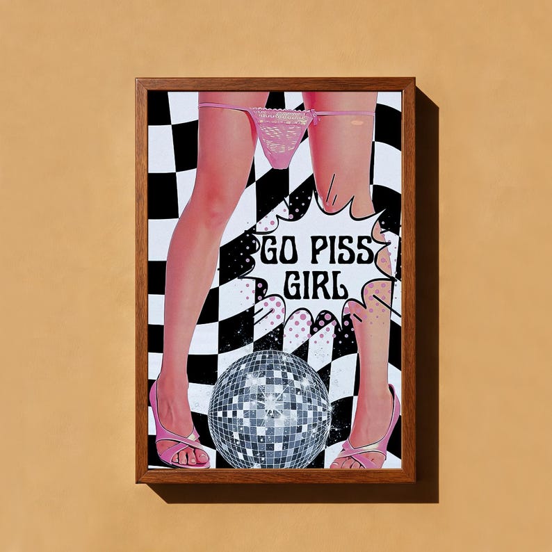 May include: Framed art print featuring a pop art style image. The artwork depicts legs in pink heels and underwear, with a disco ball and the text "GO PISS GIRL" on a black and white checkered background.