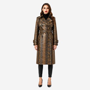 Könnte beinhalten: Ein knielanger Trenchcoat mit braun-schwarzem Schlangenledermuster, breitem Kragen, Schulterklappen und einem passenden Gürtel mit Schnalle in der Taille. Der Mantel hat lange Ärmel mit Schnallenriemen an den Manschetten und eine Knopfleiste.