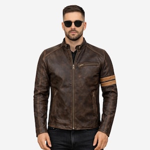 May include: Brown leather jacket with a zip-up front, a small chest pocket, and two tan stripes on the left sleeve. The jacket has a distressed look and a stand-up collar. The person in the image is wearing black sunglasses.