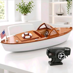 May include: A remote-controlled wooden model boat with a white hull and polished brown deck. It features a windshield, a steering wheel, a small life ring, and a miniature American flag. A black Dumas 2.4GHz remote control transmitter is included.