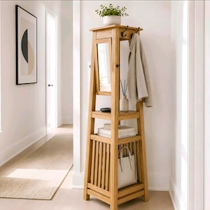 May include: A tall, light-toned wooden entryway organizer featuring a rectangular mirror, a top shelf with a potted plant, multiple open storage tiers, and side hooks. A beige jacket hangs from a hook, while a white handbag sits on the bottom shelf.