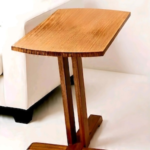 May include: A wooden side table with a rectangular top and a cross-shaped base. The table is made of a light brown wood and has a simple, modern design. The table's dimensions are approximately 24 inches long, 12 inches wide, and 26 inches high.
